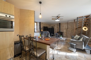A modern kitchen with a built-in oven, dining area with chairs, and a seating area with a sofa and a coffee table.