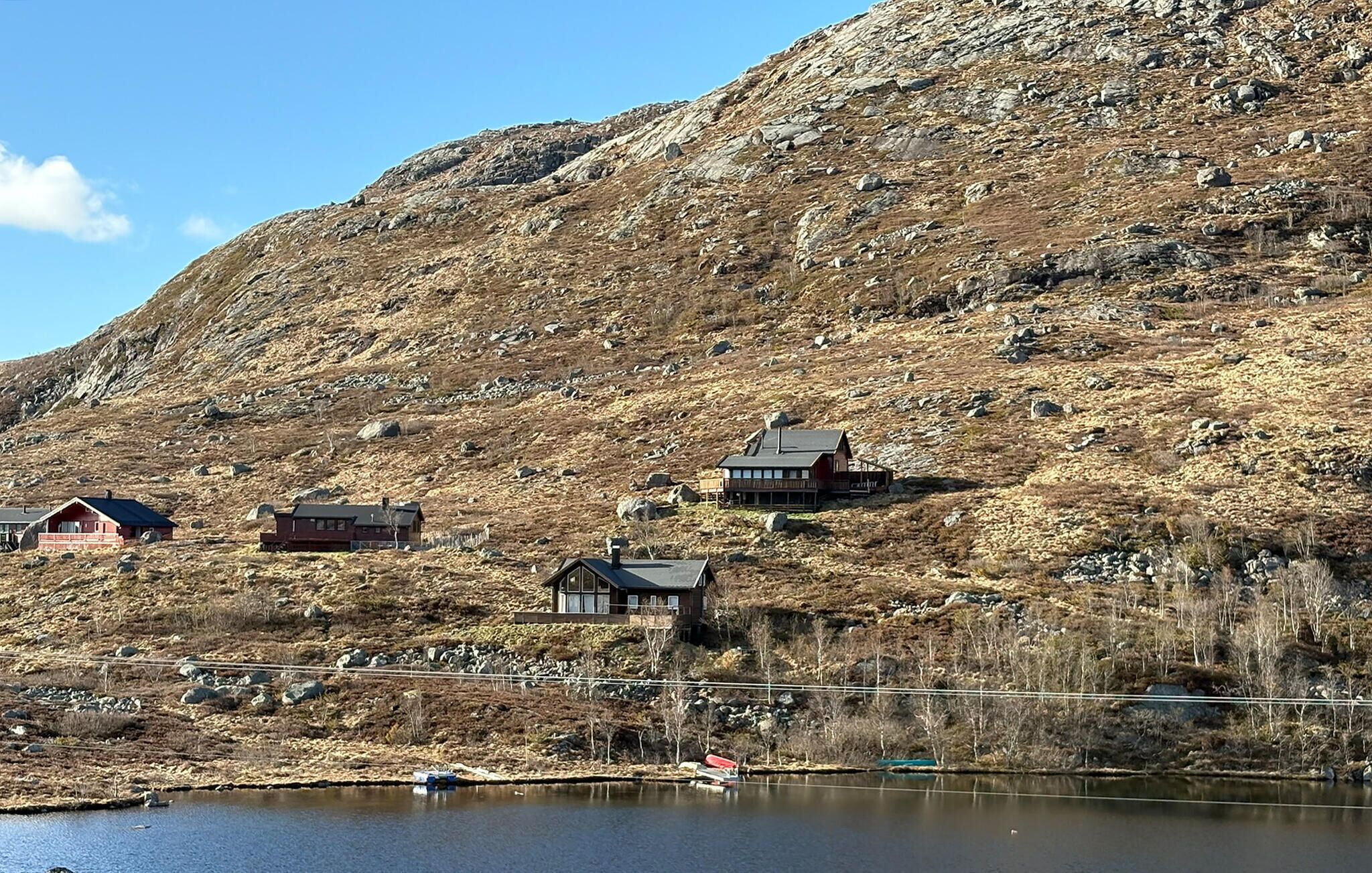 Un chalet isolé, situé au bord d’un lac et entouré d’un paysage rocheux.