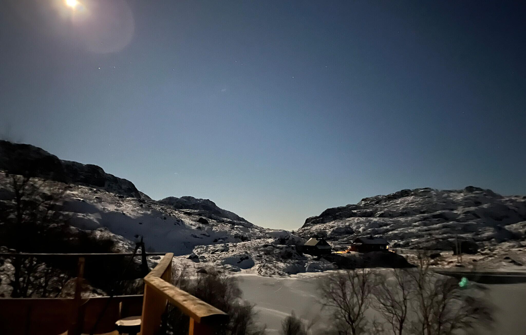 Paisaje montañoso nevado con cielo despejado y una luna.