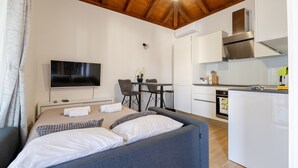A modern room with a bed, a TV, a dining table, and a kitchenette. - Holiday Home Mareta with pool (Privlaka)