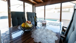 A dining area with a table set for two, featuring a fruit bowl, wine glasses, and a decorative doily. - Holiday Home Mareta with pool (Privlaka)