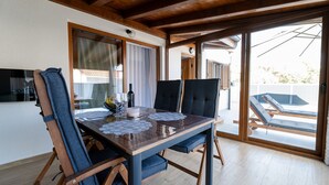 A dining area with a table set for two, chairs, a bottle of wine, and a fruit bowl. - Holiday Home Mareta with pool (Privlaka)