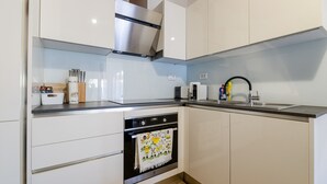 A modern kitchen with white cabinetry, stainless steel appliances, and a wooden floor. - Holiday Home Mareta with pool (Privlaka)