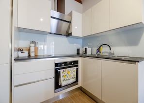 Eine moderne Küche mit weißen Schränken, Edelstahlgeräten und Holzboden.