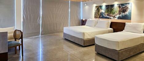 A hotel room with two beds, a chair, and a large window with curtains.