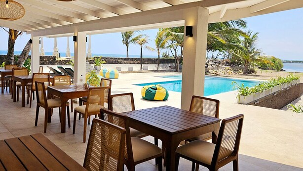 Un espace extérieur aménagé, abrité et doté de tables et de chaises, une piscine et une vue sur l’océan.