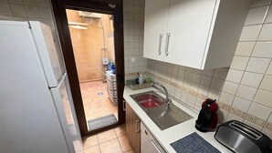 Una cocina pequeña equipada con refrigerador, lavamanos y tostadora.