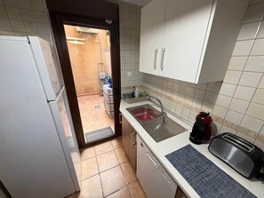 A compact kitchen with a refrigerator, sink, and toaster. - Felipe Beach Apartment (Los Cuarteros)