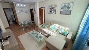 Una sala de estar con sofá, mesa de centro y un comedor con sillas.