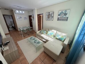 A living room with a sofa, coffee table, and a dining area with chairs. - Felipe Beach Apartment (Los Cuarteros)
