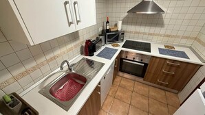 Una cocina con armarios blancos, un lavamanos de acero inoxidable, un microondas y un horno.
