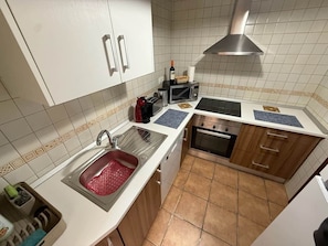 Eine Küche mit weißen Schränken, einer Edelstahl-Spüle, einer Mikrowelle und einem Backofen.