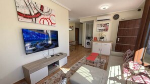 Ett modernt vardagsrum med en platt-TV, en soffa, ett soffbord och en mönstrad matta.