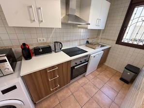 A compact kitchen with a stove, oven, dishwasher, and a coffee maker.