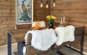 Ein Holztisch mit einer Schüssel Orangen, einer Blumenvase und Kerzen.