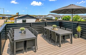An outdoor patio with dark wicker furniture, a large umbrella, and potted plants. - 3 bedroom amazing home in Hvide Sande (Hvide Sande)