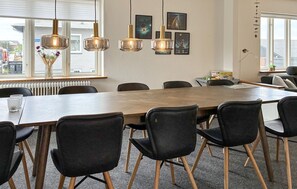A conference room with a wooden table, black chairs, and pendant lights. - 3 bedroom amazing home in Hvide Sande (Hvide Sande)