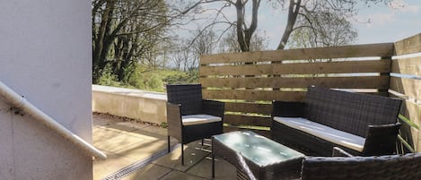 An outdoor seating area with wicker furniture and a wooden fence.