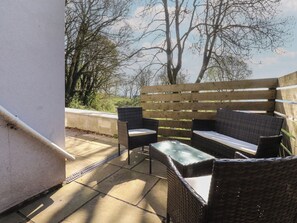 An outdoor seating area with wicker furniture and a wooden fence. - Beacon Fell Cottage 2 (Preston)