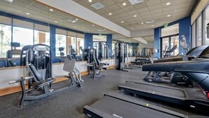 A gym with cardio equipment, weight machines, and a mirrored wall. - Walt's Disney Villa | Hot Tub & NO Resort Fees (Kissimmee)