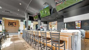 A bar area with a counter, bar stools, and a sports screen. - Walt's Disney Villa | Hot Tub & NO Resort Fees (Kissimmee)