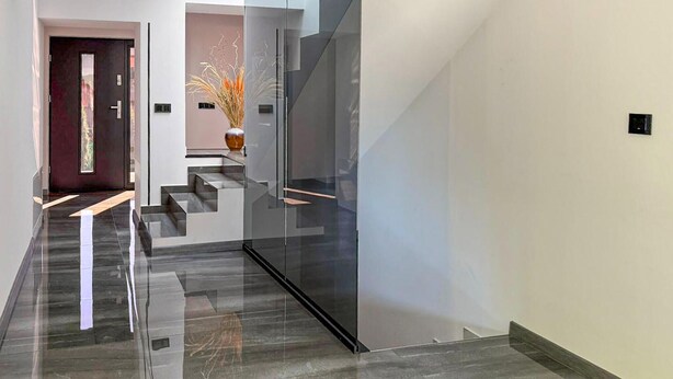 A modern interior with a glass staircase, a dark door, and a vase with dried plants. - Nice home in Wisla with house a mountain view (Wisla)