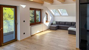 A modern loft apartment with skylights, a sectional sofa, and a large sliding glass door. - Nice home in Wisla with house a mountain view (Wisla)