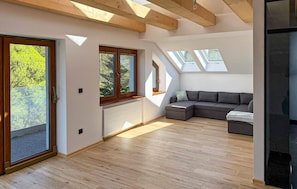 Un loft moderno con tragaluces, un sofá modular y un amplio ventanal corredera.