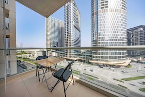 Ein Balkon mit Tisch und Stühlen mit Blick auf eine Stadtlandschaft und moderne Gebäude.