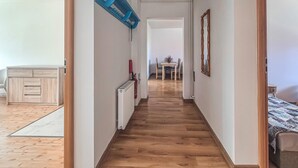 A narrow hallway with wooden flooring, a radiator, and a table with chairs in the distance. - Amazing apartment in Nowe Warpno with WiFi (Nowe Warpno)