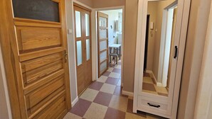 Un couloir avec un sol à carreaux, des portes en bois et une porte de placard miroir.
