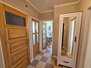 Un pasillo con piso a cuadros, puertas de madera y una puerta de armario espejada.