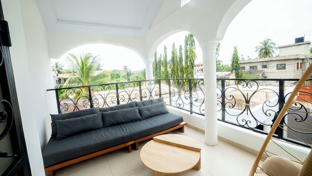A balcony with a sofa, a small table, and a hanging chair. - Villa Rosette, Calme, confort, services premiums (Lomé)