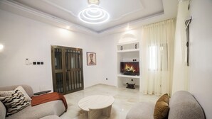 A modern living room with a fireplace, sofas, a coffee table, and a TV. - Villa Rosette, Calme, confort, services premiums (Lomé)