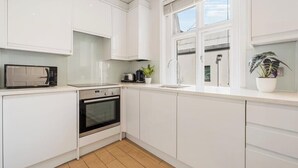 Eine moderne Küche mit weißen Schränken, einer Mikrowelle, einem Toaster und einem Spülbecken.