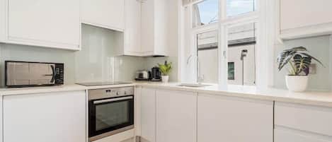 Une cuisine moderne avec des meubles blancs, un four à micro-ondes, un grille-pain et un évier.