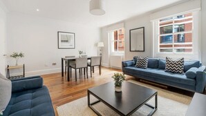 Ein modernes Wohnzimmer mit einem blauen Sofa, einem Couchtisch und einem Essbereich mit Stühlen und einem Tisch.