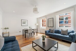 Ein modernes Wohnzimmer mit einem blauen Sofa, einem Couchtisch und einem Essbereich mit Stühlen und einem Tisch.