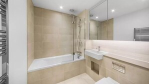 Ein modernes Badezimmer mit einer gläsernen Dusche, einer weißen Badewanne und einem Waschbecken mit Spiegel darüber.