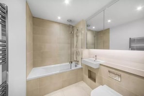 Ein modernes Badezimmer mit einer gläsernen Dusche, einer weißen Badewanne und einem Waschbecken mit Spiegel darüber.