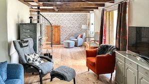 Ein gemütliches Wohnzimmer mit Kamin, Fernseher und einer Treppe, die in einen anderen Raum führt.