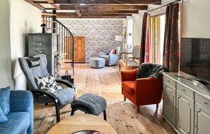 A cozy living room with a fireplace, a television, and a staircase leading to another room. - Nice home in Fjälkinge (Fjälkinge)