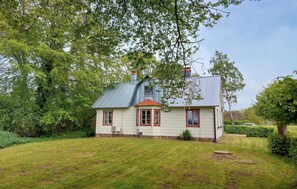 Ein Haus mit geneigtem Dach, einem Schornstein und einer kleinen Veranda.