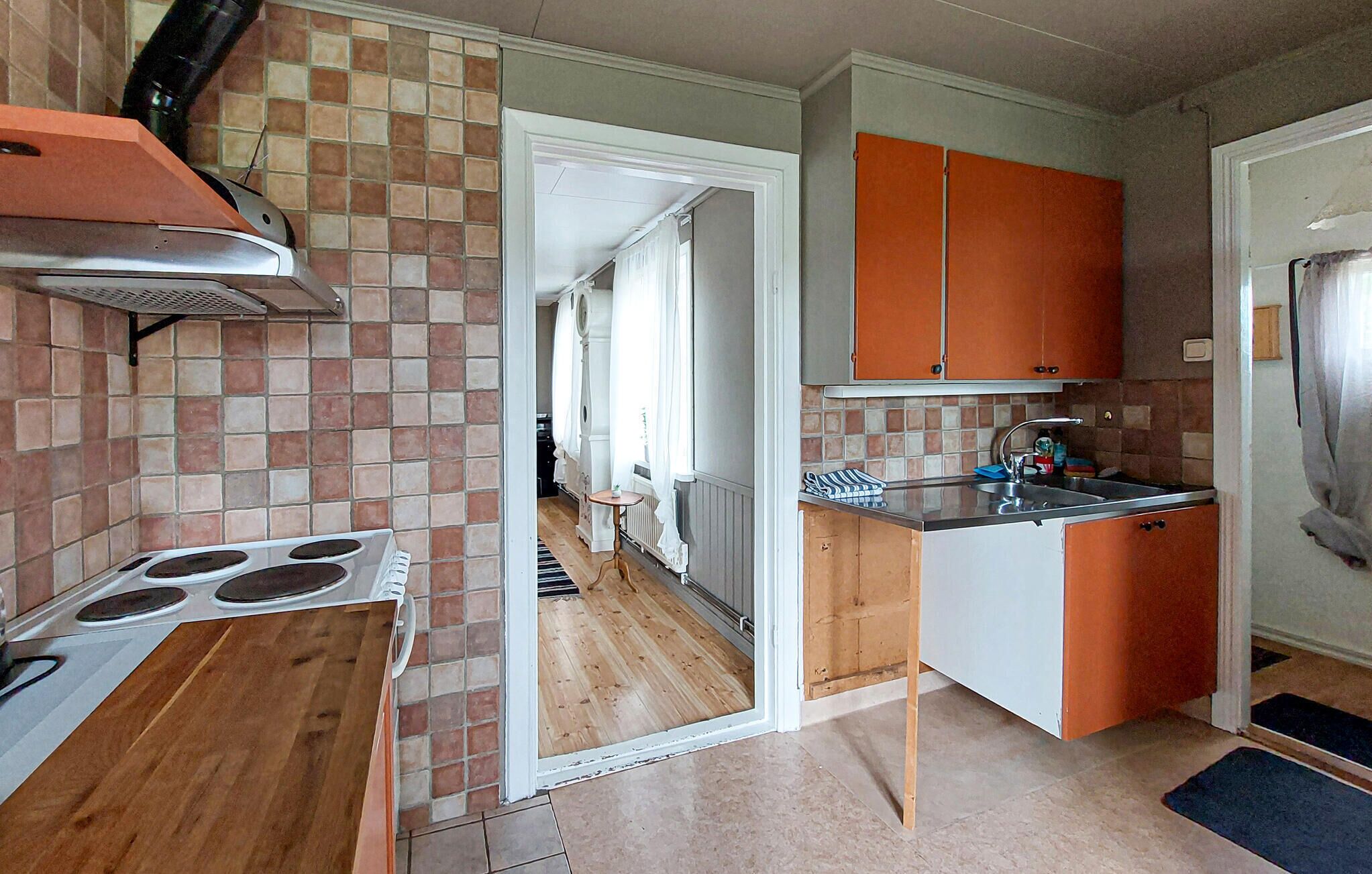 Ett kompakt kök med en spis, en diskho och orange skåp.