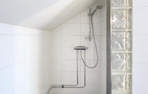 A shower with chrome fixtures and clear glass panels.