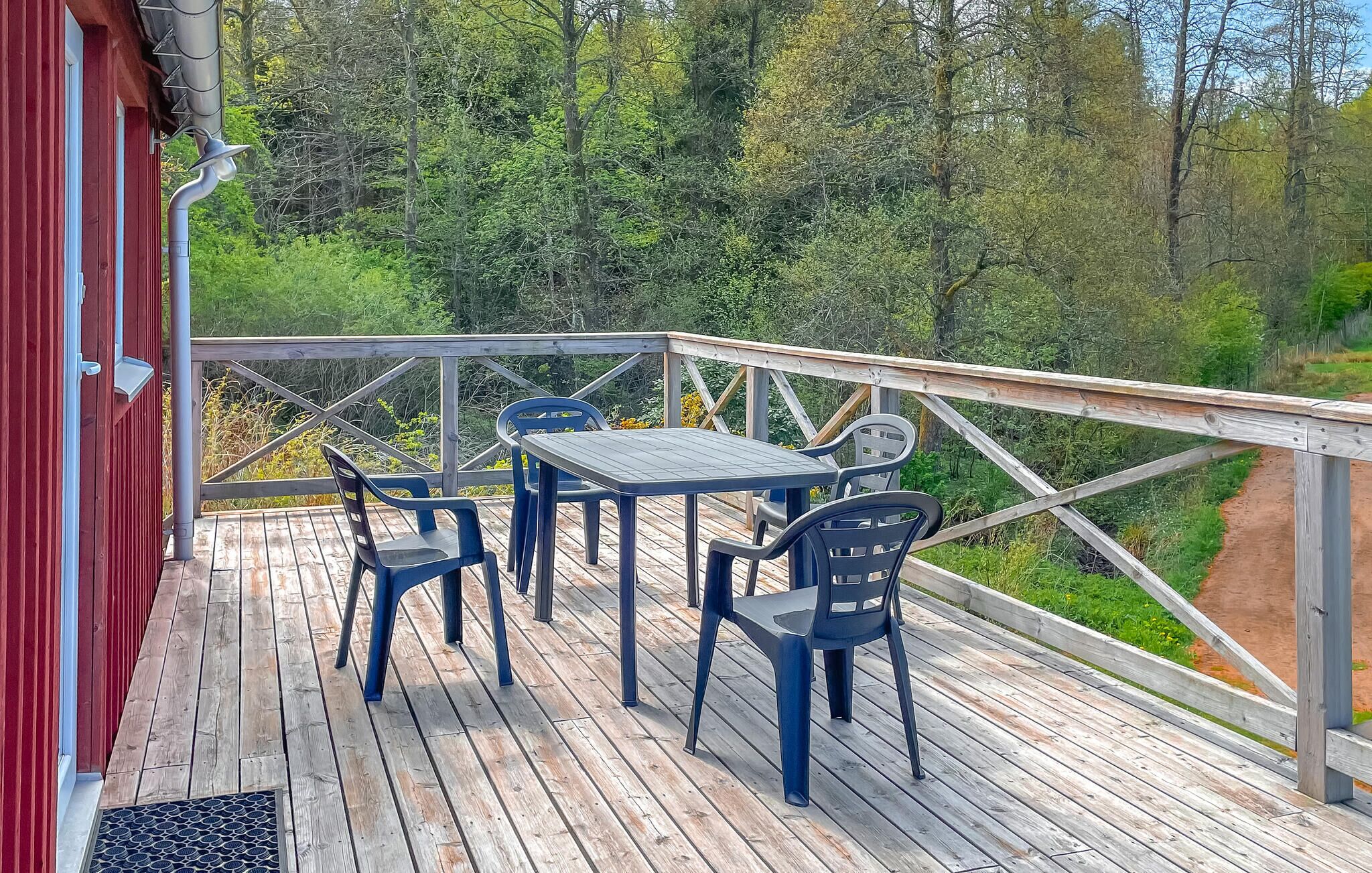 A wooden deck with outdoor furniture, a railing, and a view of a forested area.