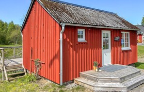 A red wooden building with a white door, windows, and a small porch.