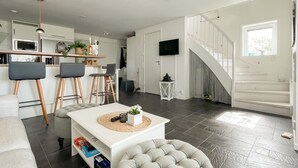 Een moderne leefruimte met keuken, eethoek en trap.