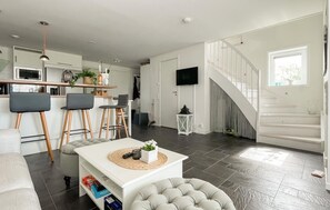 A modern living space with a kitchen, dining area, and staircase.