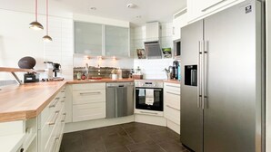Een moderne keuken met witte kastjes, een roestvrijstalen koelkast, een vaatwasser en een inbouwoven.